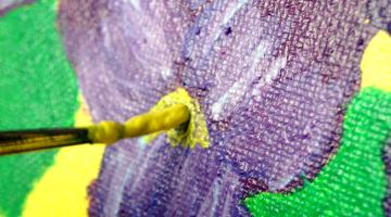 painting on canvas with yellow paint on brush