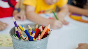 children colouring and pencils in metal bucket