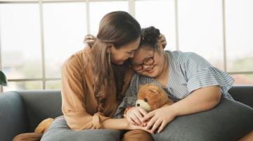 Child cuddling parent and toy bear