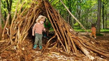 Boy playing in forest school wooden tent