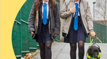 2 young adults walking alongside a guide dog