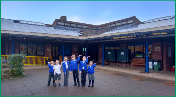 children in front of their school with solar panels